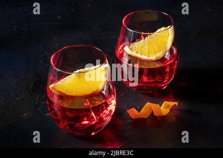 Cocktail Campari und aperol mit orangefarbener Garnierung auf schwarzem Schiefergrund. Alkoholisches Getränk Stockfoto