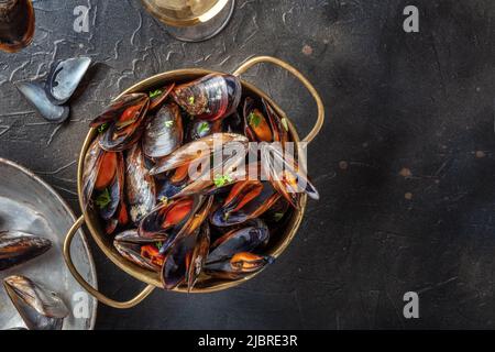 Muscheln mit Weißwein, von oben auf einem schwarzen Schieferhintergrund mit Kopierfläche aufgenommen Stockfoto