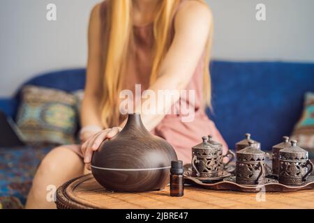 Aromatherapie-Konzept. Holz Elektro Ultraschall ätherisches Öl Aroma Diffusor und Befeuchter. Ultraschall Aroma Diffusor für zu Hause. Frau, die sich ausruhte Stockfoto