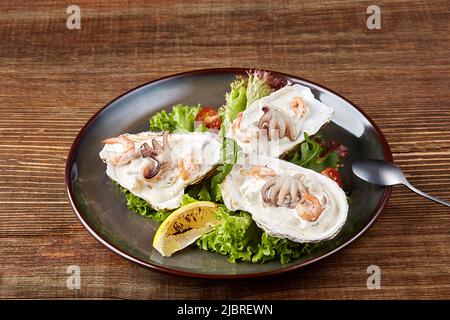 Frischer Fisch-Cocktail auf einem schwarzen Teller auf einem hölzernen Hintergrund Stockfoto