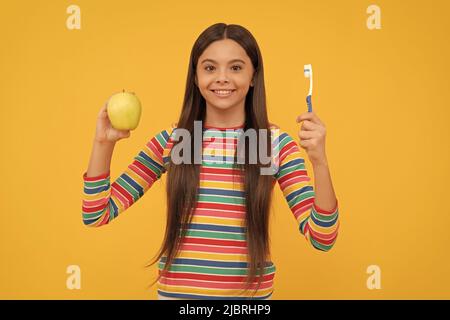 Mundhygiene beachten. Glückliches Mädchen halten Apfel und Zahnbürste. Mundhygiene. Zahnpflege Stockfoto