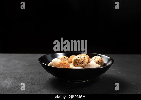 Schwarzer Teller mit asiatischem Dessert auf dunklem Hintergrund Stockfoto