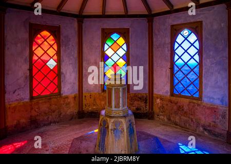 Farbbild des Inneren eines farbenfrohen, sonnendurchfluteten Pavillons mit Bogenfenstern im alten arabischen Stil und geometrischem Glasmosaik in islamischer Architektur. Stockfoto