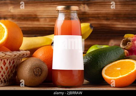 Fruchtgetränk in Glasflasche und Obst auf Holzboden Stockfoto