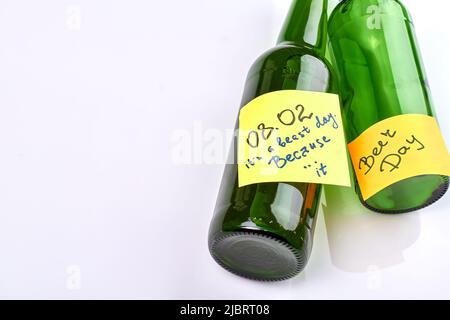 Glasbierflaschen mit Stickernotizen isoliert auf weißem Hintergrund. Der Biertag ist ein Tag der Bestie. Stockfoto