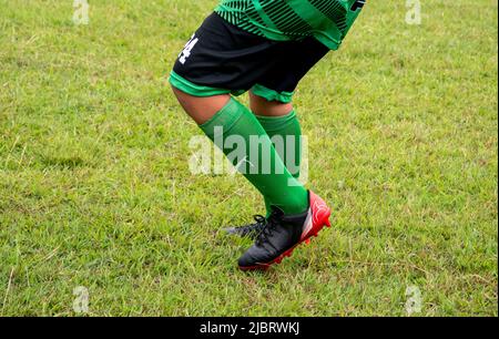 Fußballspieler in Fußballschuhen beim Gehen auf Gras mit selektivem Fokus. Stockfoto