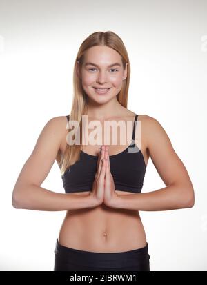 Lächelnder Yogalehrer mit namaste Geste, Training im Fitnessstudio, Meditation in Sportbra und Leggings, weißer Hintergrund Stockfoto