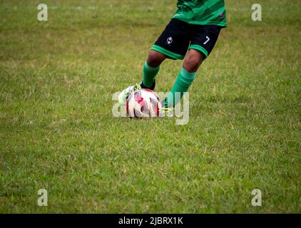 Fußballspieler in Fußballschuhen beim Gehen auf Gras mit selektivem Fokus. Stockfoto
