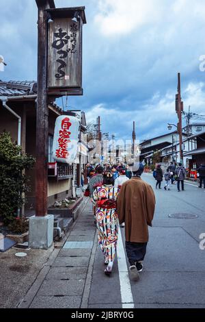 Frauen, die wie Geisha auf der Straße des Arashiyama Bezirks in der Nähe des Bambuswaldes gekleidet sind Stockfoto