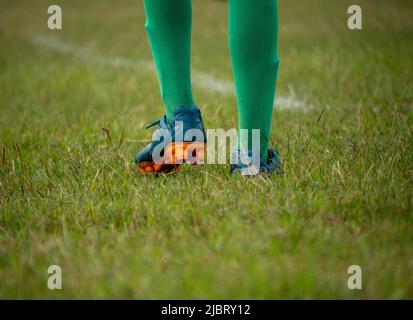 Fußballspieler in Fußballschuhen beim Gehen auf Gras mit selektivem Fokus. Stockfoto