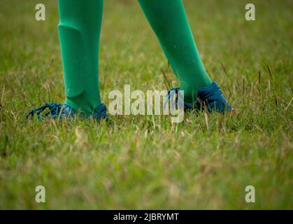 Fußballspieler in Fußballschuhen beim Gehen auf Gras mit selektivem Fokus. Stockfoto