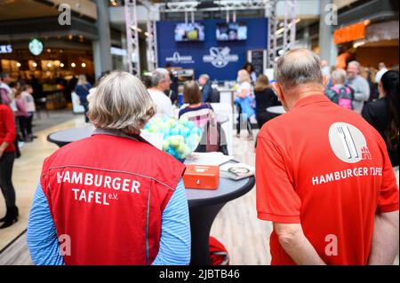 Hamburg, Deutschland. 08.. Juni 2022. Kirsten (l.) und Jens, ehrenamtliche Helfer der Hamburger Tafel, sind bei der Kochaktion dabei, Spenden zu sammeln. In der Europa-Passage findet eine Wohltätigkeitsveranstaltung statt, um der bedürftigen Hamburger Tafel ein wenig zu helfen. Bis Samstag kochen dort Prominente mittags ihre Lieblingsgerichte für Besucher des Einkaufszentrums. Quelle: Jonas Walzberg/dpa/Alamy Live News Stockfoto