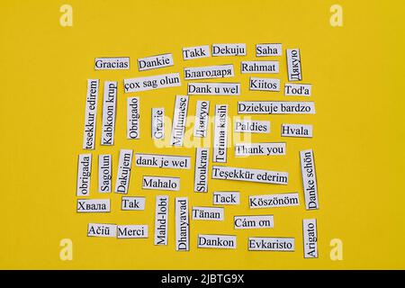 Vorträge mit Dankeschön in vielen verschiedenen Sprachen. Isoliert auf gelbem Hintergrund. Draufsicht flach liegend. Stockfoto