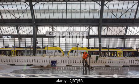 Karlsruhe, Deutschland - 28. Aug 2021: Inneneinrichtung des Karlsruher Hauptbahnhofs mit Schild 'Karlsruhe HBF'. Mit Bauarbeiter und Zug. Stockfoto