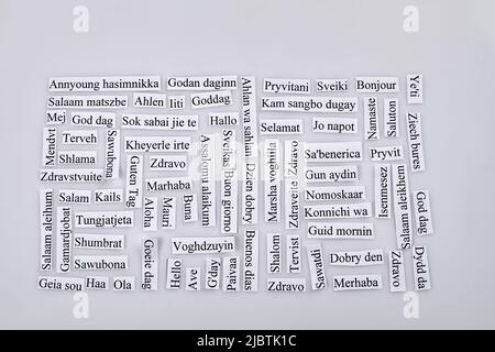 Papierstücke mit Hello-Wort in vielen verschiedenen Sprachen. Mehrsprachige Begrüßung auf weißem Hintergrund. Stockfoto