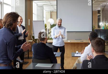 Der stolze Chef bei der Teambesprechung im Büro applaudiert seinem Untergebenen und gratuliert ihm zu seinem Job Gut gemacht. Stockfoto