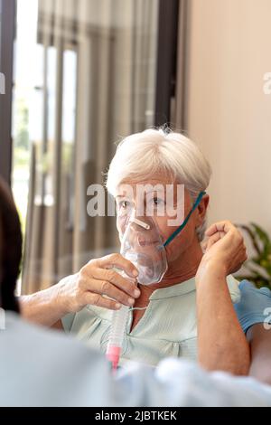 Kaukasische ältere Frau mit Sauerstoffmaske sitzt auf einem Rollstuhl zu Hause Stockfoto