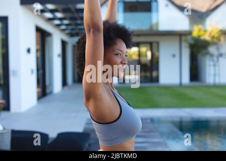 Nahaufnahme einer jungen afroamerikanischen Frau, die in der Nähe des Pools Yoga praktiziert Stockfoto