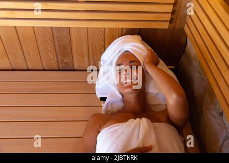 Kaukasische junge Frau im Bademantel, die sich in der Sauna entspannt Stockfoto