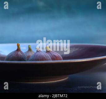 Violette Keramikschale mit vier Feigen auf hellblauem Hintergrund Stockfoto