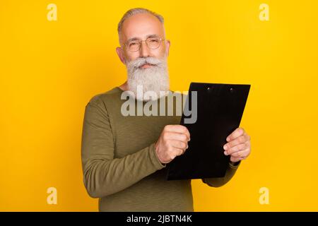 Porträt von attraktiven erfahrenen grauhaarigen Mann hält in den Händen Zwischenablage isoliert über hellen gelben Hintergrund Stockfoto