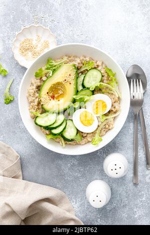 Haferbrei mit gekochtem Ei, Gurke und Avocado Stockfoto