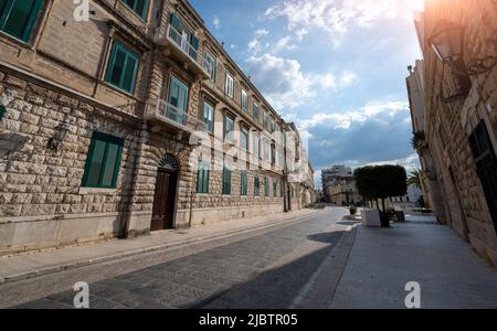 Trani, Apulien, Italien. August 2021. Eine charmante Straße im historischen Zentrum mit Blick auf historische Häuser mit grünen Fenstern. Schöner Sommertag mit Stockfoto