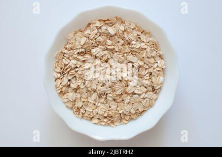 Natürliche Haferflocken, Draufsicht auf gesundes und nahrhaftes Getreide in weißer Schale. Beliebtes Morgenessen isoliert auf weißem Hintergrund. Stockfoto