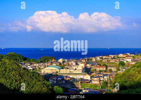 Die Nachmittagssonne trifft auf ein kleines Küstendorf, während Wolken in der Ferne wölben Stockfoto