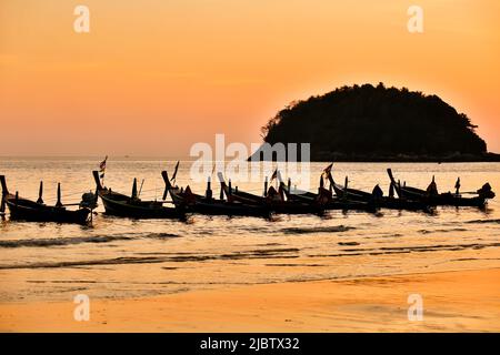 Longtail-Boote bei Sonnenuntergang am Kata Beach auf der Insel Phuket in der Provinz Phuket, Thailand. Stockfoto