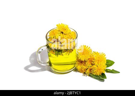Tasse Tee mit den auf weißem Hintergrund isolierten Delelionblüten. Frühstück Frühling Konzept, trendy Stil, alternative Medizin. Ein hartes Licht, dunkel Stockfoto