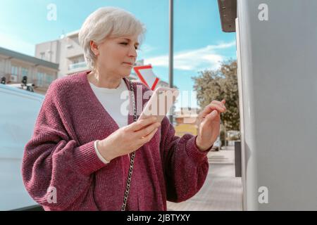 Weiblich mit dem Handy an der Tankstelle Stockfoto