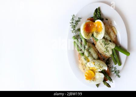 Spargel, Eier und Käsebruschetta auf weißem Hintergrund. Direkt darüber. Gesunde Ernährung. Stockfoto