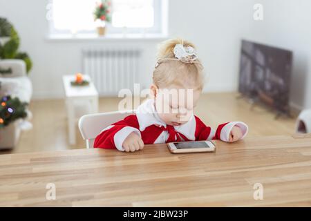 Taubes Mädchen mit Cochlea-Implantat im Wohnzimmer mit weihnachtsbaum - Taubheitsvielfalt und innovative Hörgerätetechnologien Stockfoto