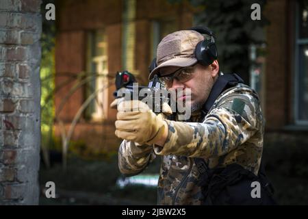 Kampftrainingssoldat der Spezialeinheiten. Mann in Militärmunition steht in Wache. Militärangehöriger verstecken sich in Position mit Waffe in den Händen. Ranger während der Militäroperation. Stockfoto