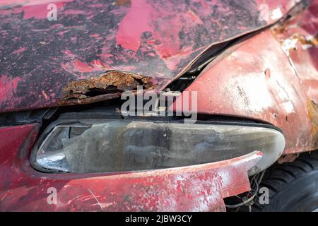 Broken headlights as a result of a collision. Broken red car after an accident. Car accident concept. Damaged emergency headlight, hood and bumper. Da Stockfoto