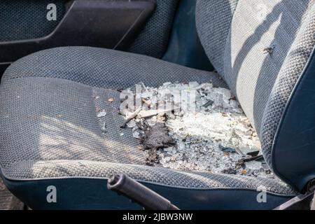 Der Innenraum des Fahrzeugs ist nach dem Unfall beschädigt, zerbrochenes Glas auf dem Sitz. Beschädigter Innenraum Stockfoto