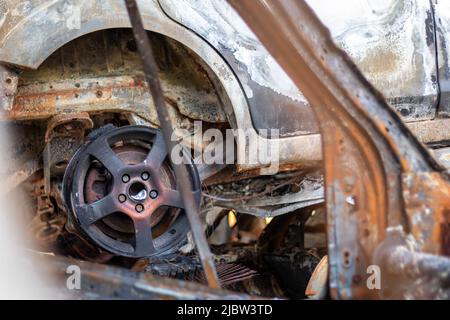 Autos nach dem Feuer. Eiserne Teile eines verbrannten Autos. Ausgebrannte Autos, die auf der Seite einer ruhigen Landschaft stehen. Explosion, die Folge eines Feuers. Auto insu Stockfoto