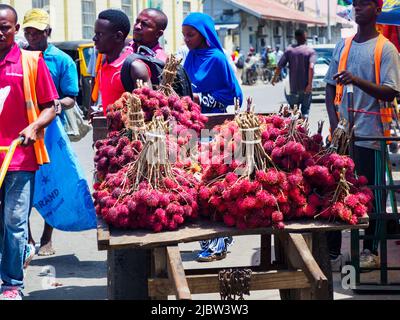 Sansibar, Tansania - Februar 2021: Viele rote Litschis werden direkt von einem Holzkarren in der Straße Afrikas verkauft. Andere berühmte Namen: Lychee, longan, Stockfoto