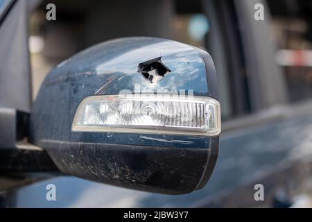 Nahaufnahme gebrochener linker Rückspiegel eines Autos in Blau. Kfz-Versicherungskonzept. Gebrochene Seitenscheibe des Fahrzeugs auf der Fahrerseite als Folge eines Stockfoto