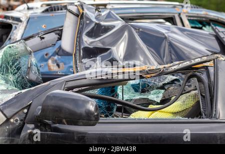 Viele kaputte Autos nach einem Verkehrsunfall auf dem Parkplatz einer Reparaturstation auf der Straße. Werkstatt für Karosserieschäden im Freien. Verkauf von Versicherten Stockfoto