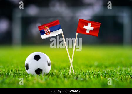 Serbien vs. Schweiz, Stadion 974 Fußballspiel-Tapete, Handgefertigte Nationalflaggen und Fußball auf grünem Gras. Fußballstadion im Hintergrund. Stockfoto