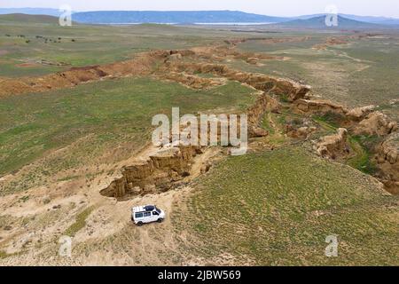 Luftviev des Vierradantriebs, der auf einer unbefestigten Straße in einer kleinen Schlucht auf dem Weg von Dedoplas Tskaro nach Takhti-TEPHA Mud Volcanoes, Georgia, fährt Stockfoto