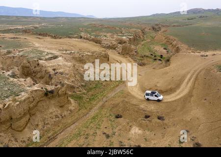 Luftviev des Vierradantriebs, der auf einer unbefestigten Straße in einer kleinen Schlucht auf dem Weg von Dedoplas Tskaro nach Takhti-TEPHA Mud Volcanoes, Georgia, fährt Stockfoto