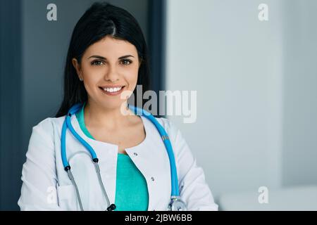 Allgemeinmediziner. Lächelnde Ärztin in medizinischer Uniform mit Stethoskop steht im Krankenhaus Stockfoto