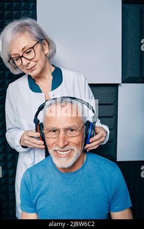 Audiometrie, Test des reinen Tonaudiogramms. Audiologe, der Höruntersuchungen beim reifen Mann in der schalldichten audiometrischen Kabine macht Stockfoto