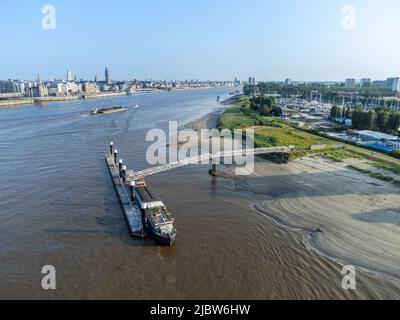 Das Schiff liegt auf dem Ponton an der Schelde in Antwerpen mit einem Lastkahn und anderen Booten im Hintergrund. Die Stadt Antwerpen auf der einen Seite, Linkeroever gegenüber Stockfoto