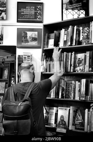 Ein Kunde durchliest die große Auswahl an Büchern, die im berühmten City Lights Booksellers Shop in San Francisco, Kalifornien, zum Verkauf stehen. Stockfoto