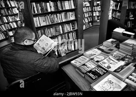 Ein Mann entspannt sich und durchmacht ein Buch im berühmten City Lights Booksellers Shop in San Francisco, Kalifornien. Stockfoto