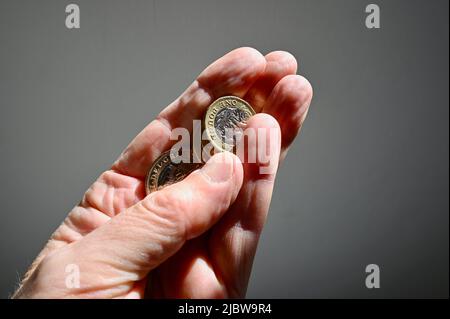 Nahaufnahme von britischen Sterling-Münzen, die in der Hand eines hochrangigen Mitarbeiters gehalten werden. Stockfoto